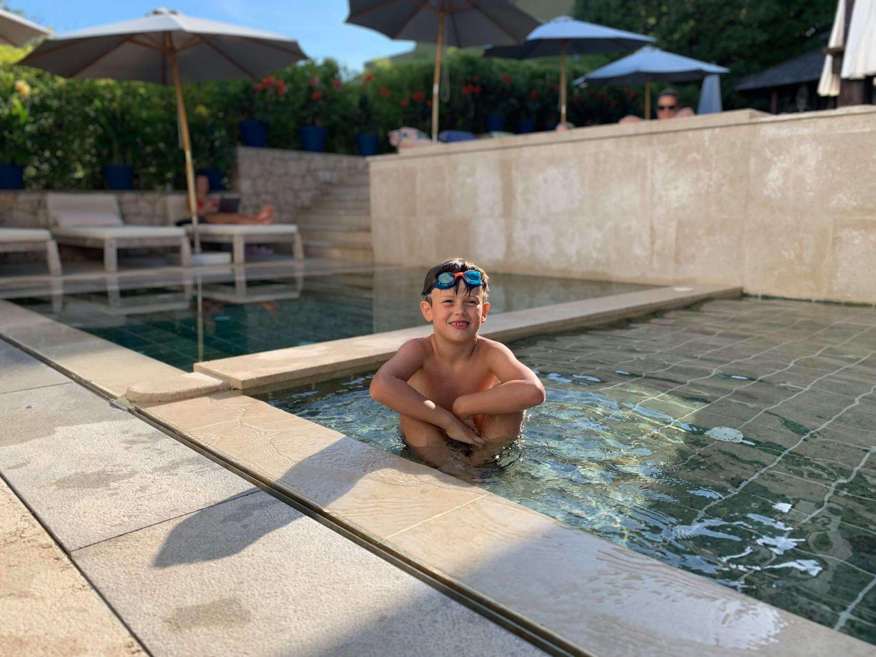 Child wearing goggles in a hotel outdoor pool ideal for family-friendly Auckland stays
